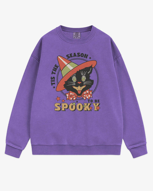 Flat lay violet 'Tis The Season To Be Spooky' sweatshirt with retro Halloween graphic of a grinning black cat with hat.