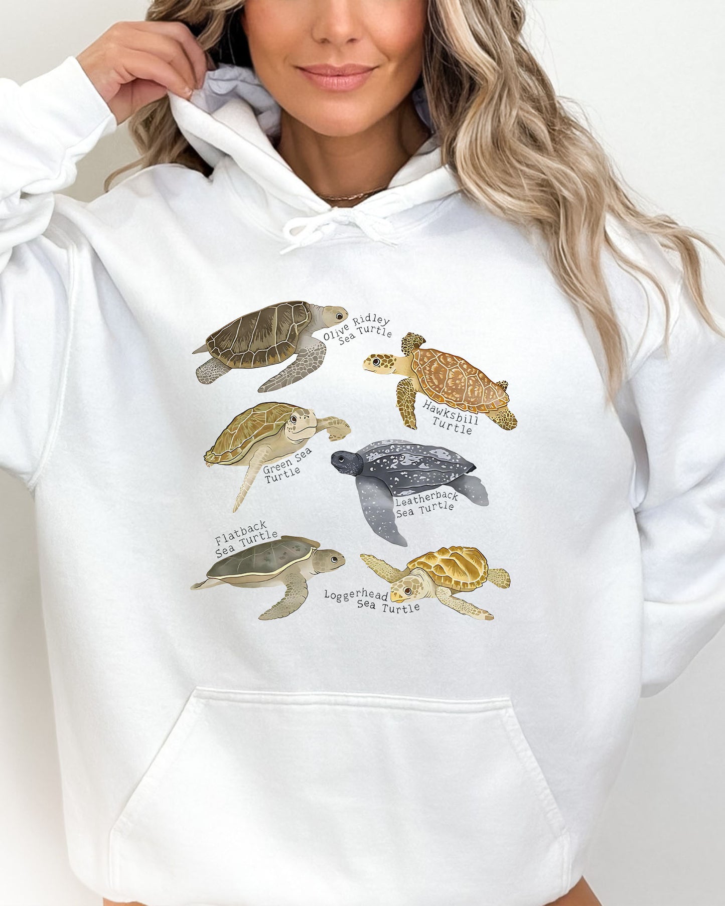 Woman wearing a white hoodie featuring a vintage-style graphic of various turtle species with their specific names.