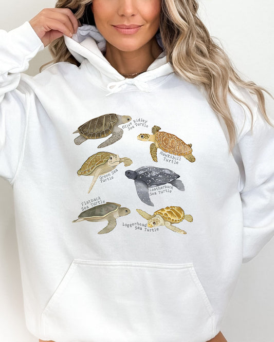 Woman wearing a white hoodie featuring a vintage-style graphic of various turtle species with their specific names.