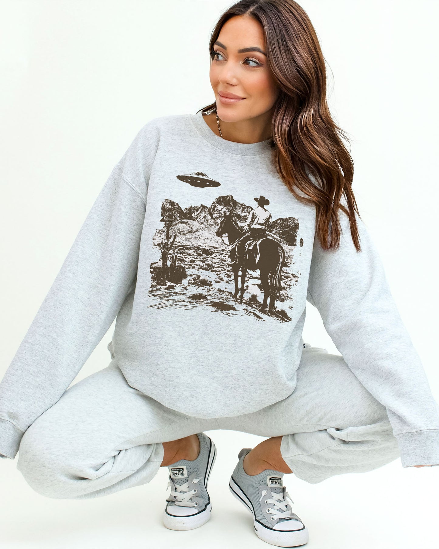 Woman wearing an ash gray UFO western graphic sweatshirt.