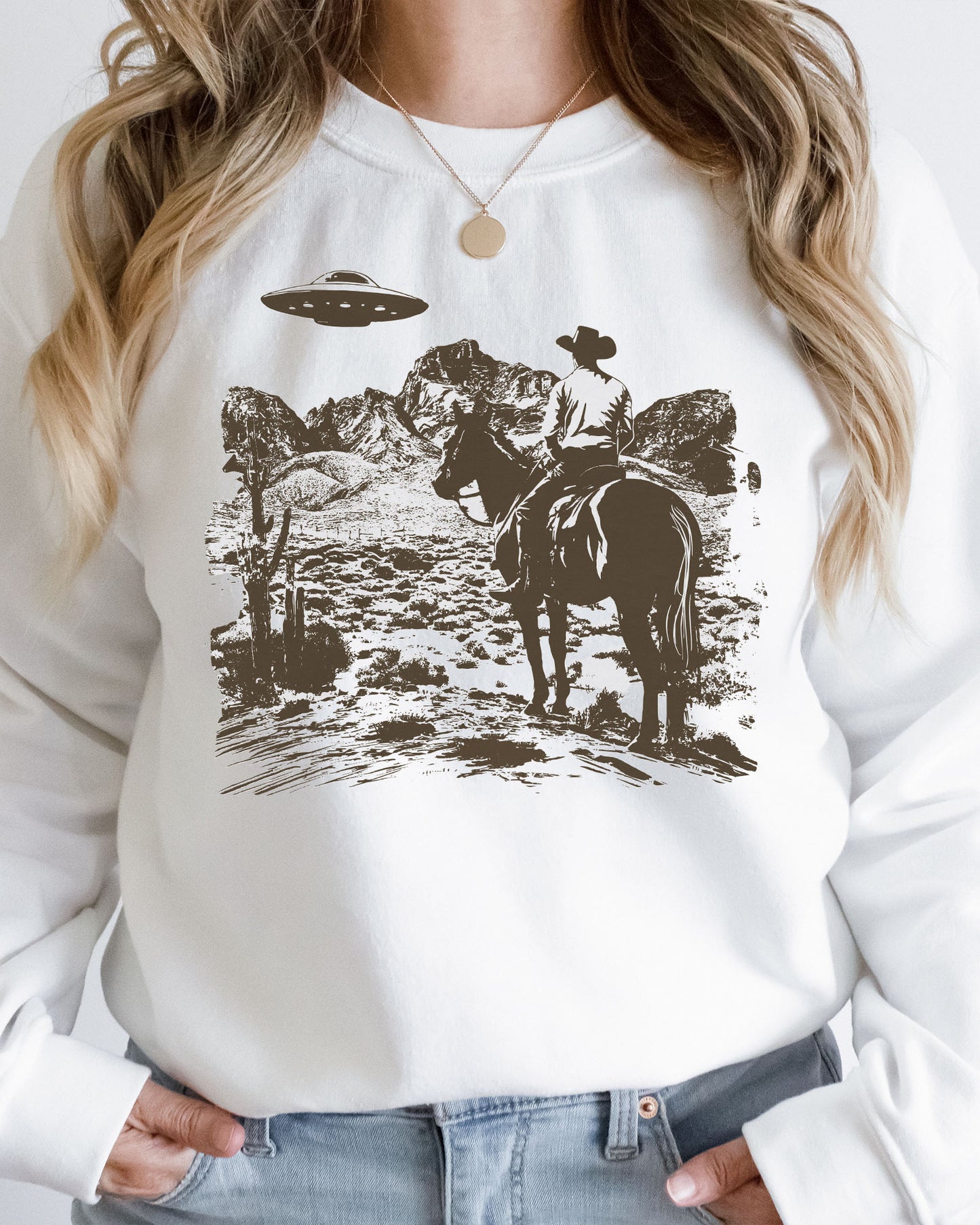 Woman wearing a white UFO western graphic sweatshirt.