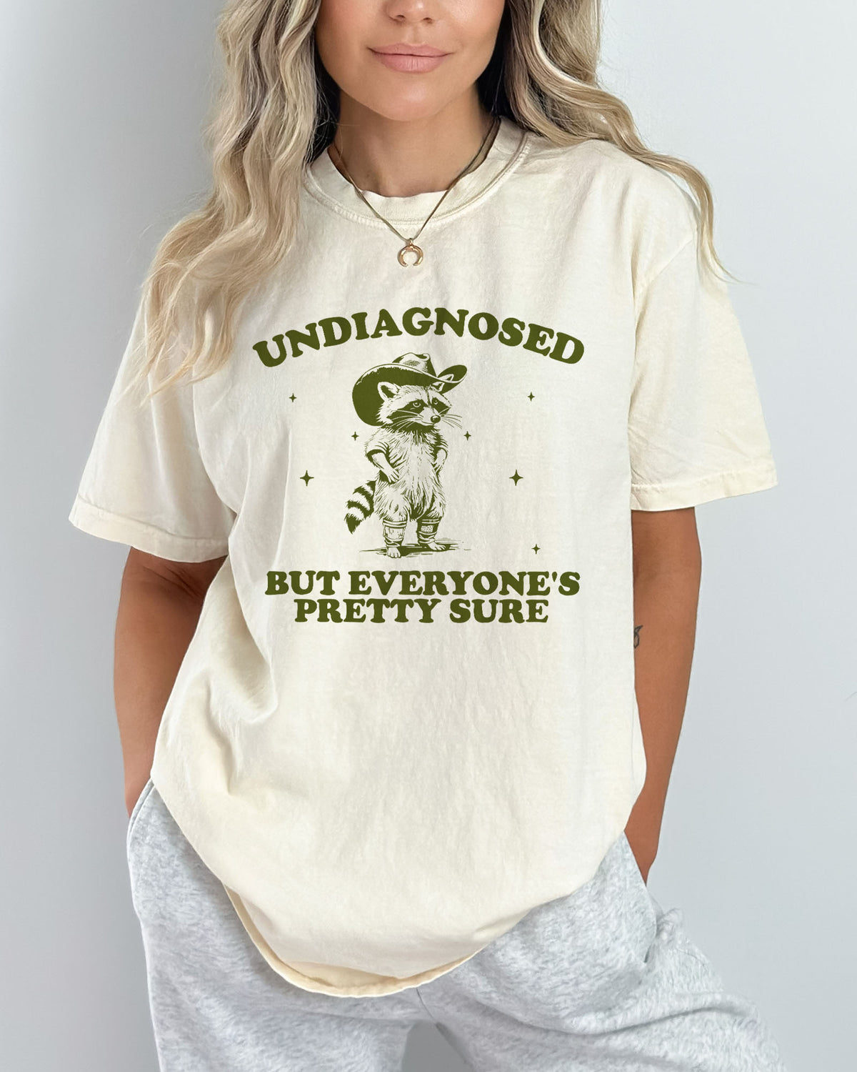 Model wearing natural color shirt with 'Undiagnosed But Everyone Is Pretty Sure' graphic design