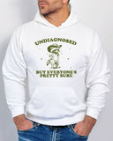 Man wearing white hoodie with a funny retro cowboy raccoon graphic and the quote 'Undiagnosed, But Everyone's Pretty Sure'.