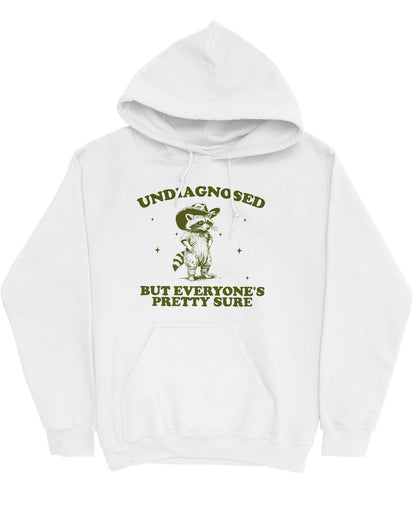 Flat lay white hoodie with a funny retro cowboy raccoon graphic and the quote 'Undiagnosed, But Everyone's Pretty Sure'.