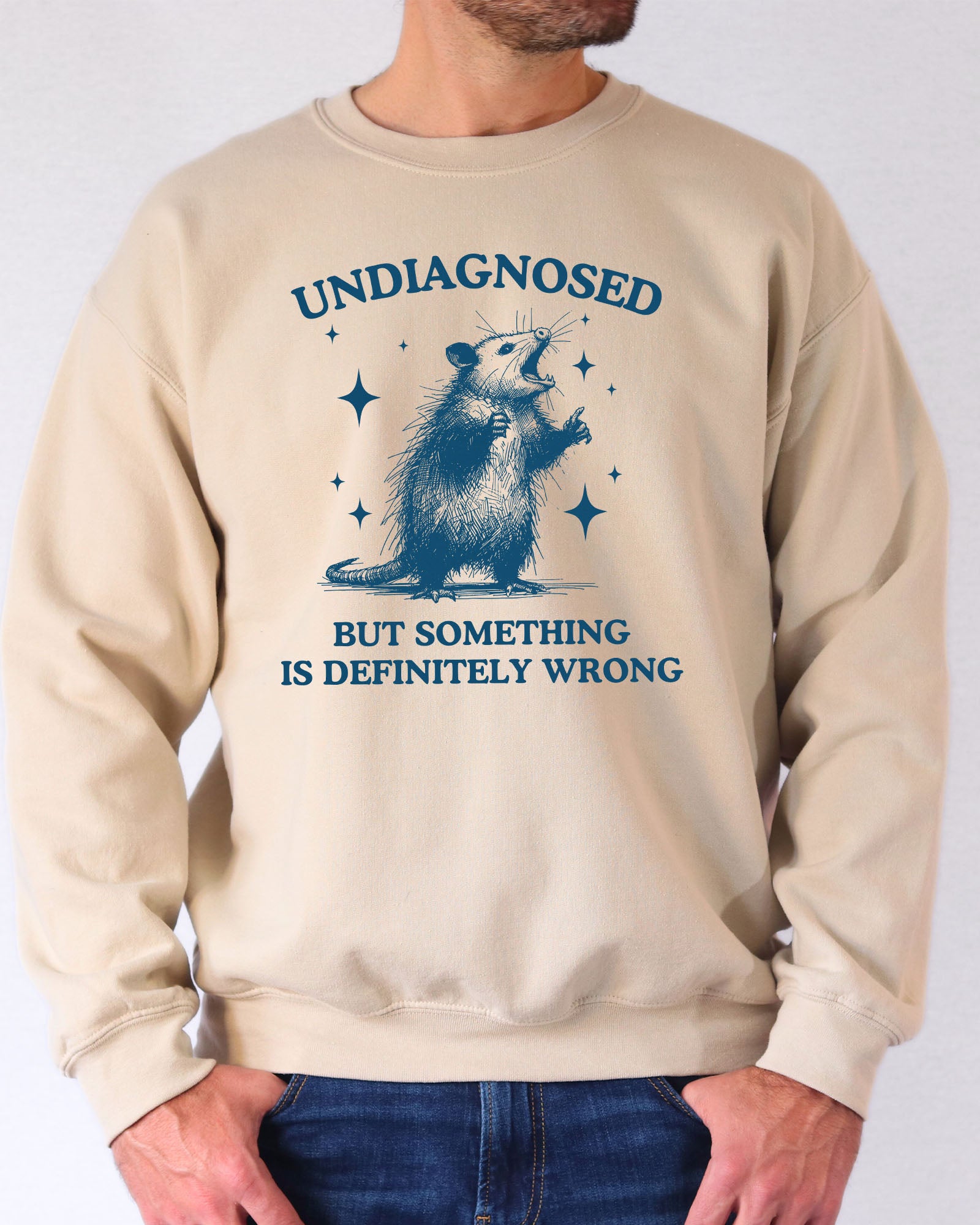 Model wearing sand color sweatshirt with 'Undiagnosed, But Something Is Definitely Wrong' graphic design