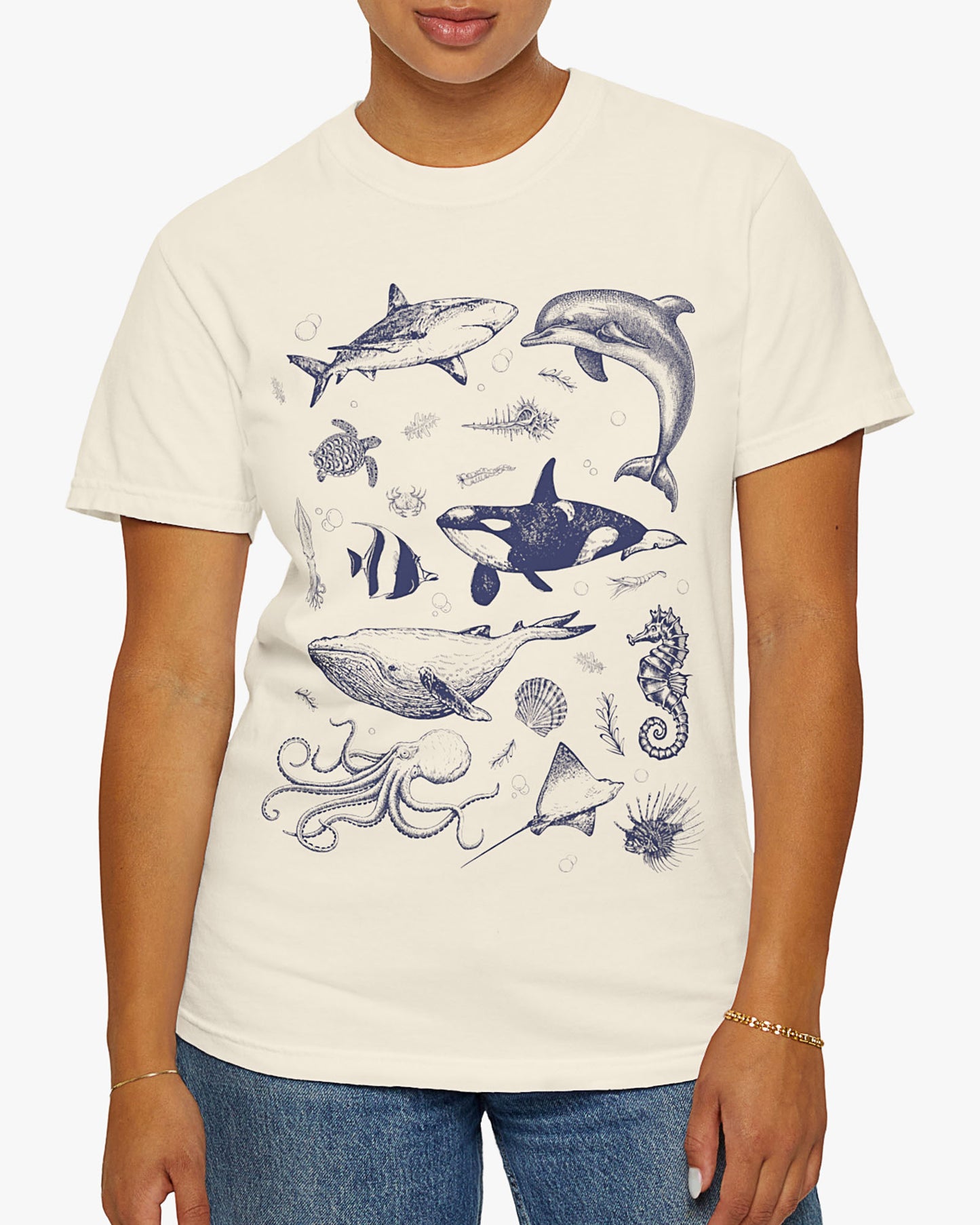 Woman wearing a natural shirt featuring a vintage 90s sea creatures collage graphic with whales, dolphins, turtles, and ocean life, perfect for retro nature lovers