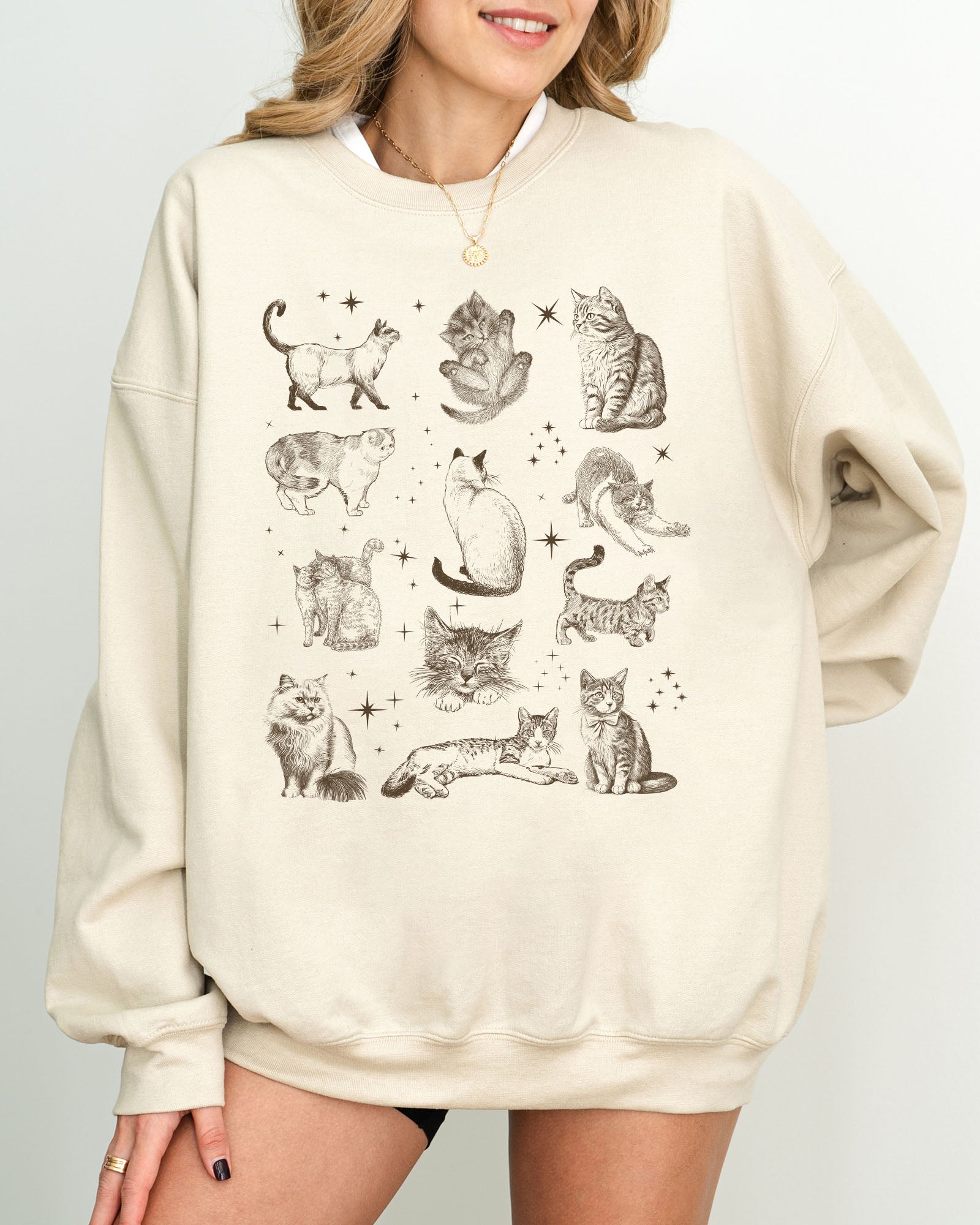 Model wearing sand color sweatshirt with vintage cat collage graphic design