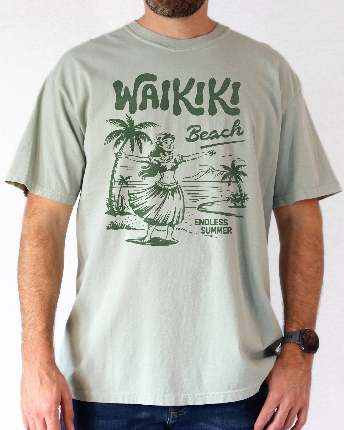 Woman wearing a bay "Waikiki Beach – Endless Summer" shirt with a retro graphic of a Hawaiian beach and a girl.