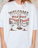 Close-up of woman wearing an ivory 'Welcome To The Wild West' shirt with a retro western graphic of a desert and cactus.