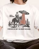 Close-up of "Well Partner I Reckon We Ain't In Kansas Anymore" shirt and a funny retro graphic of a cowboy riding a horse through a desert with an UFO appearing.