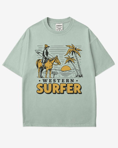 Flat lay bay 'Western Surfer' shirt with a retro graphic of a cowboy on a horse in a desert, following a beach signpost.
