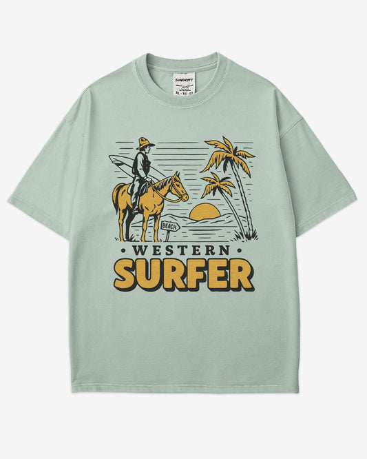 Flat lay bay 'Western Surfer' shirt with a retro graphic of a cowboy on a horse in a desert, following a beach signpost.