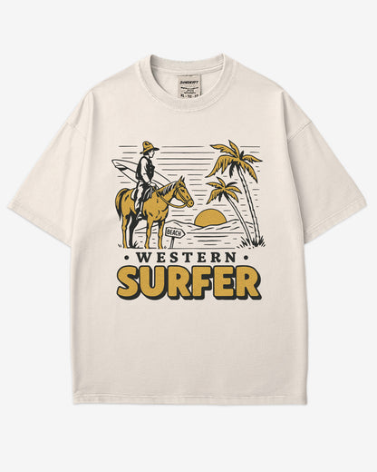 Flat lay ivory 'Western Surfer' shirt with a retro graphic of a cowboy on a horse in a desert, following a beach signpost.
