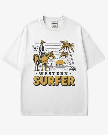 Flat lay white 'Western Surfer' shirt with a retro graphic of a cowboy on a horse in a desert, following a beach signpost.
