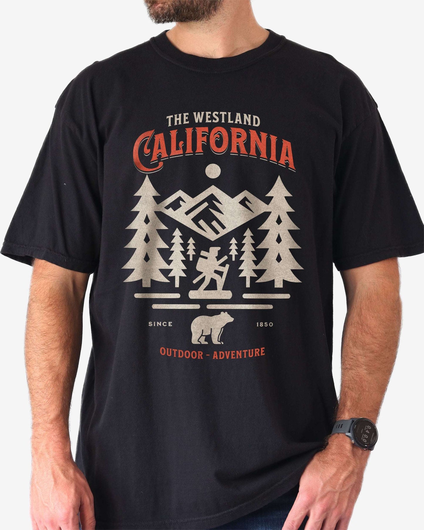 Man wearing a black Westland California Outdoor Adventure shirt with a retro vector graphic of a hiker, bear, and mountains.