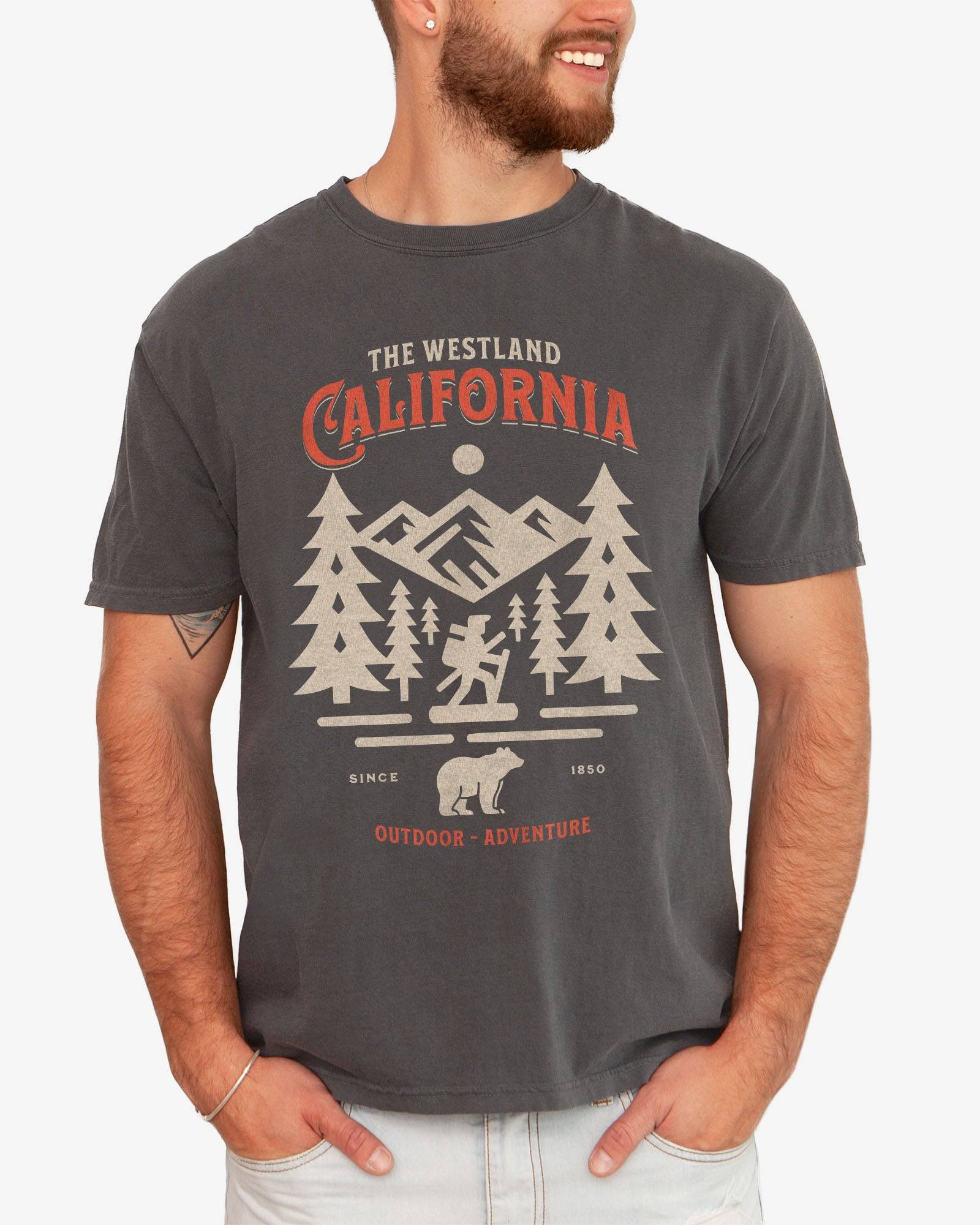 Man wearing a pepper Westland California Outdoor Adventure shirt with a retro vector graphic of a hiker, bear, and mountains.