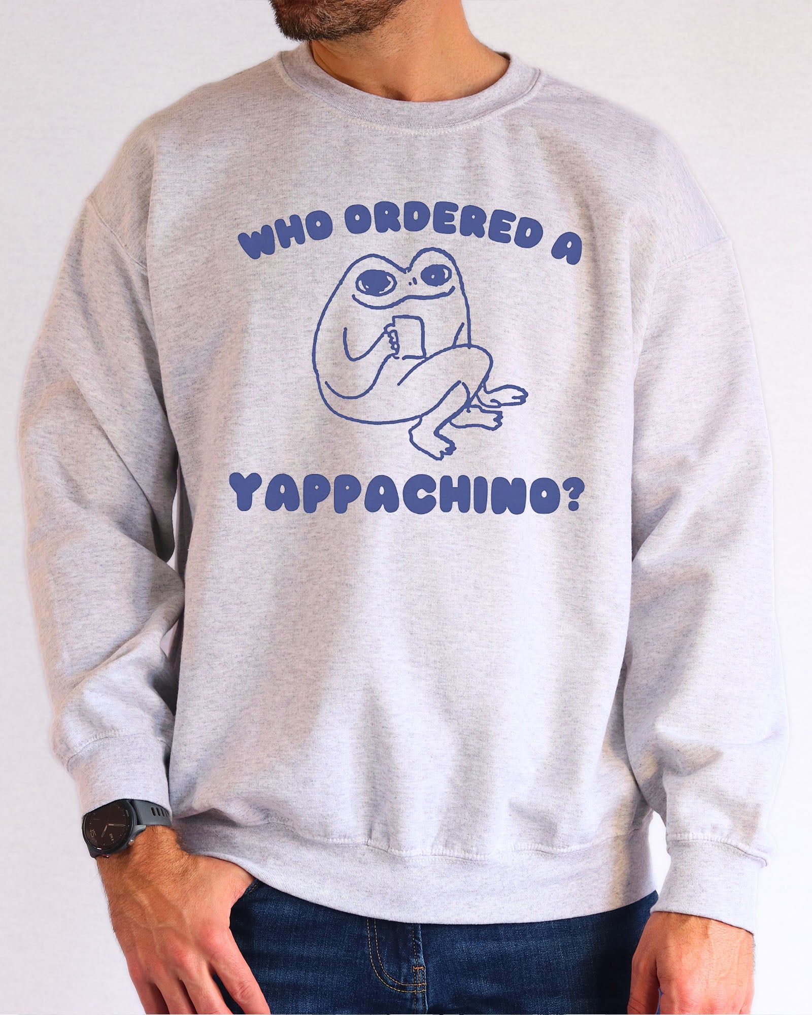 Model wearing ash color sweatshirt with 'Who Ordered A Yappachino' graphic design