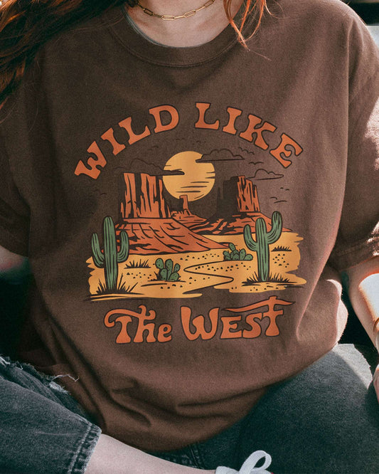 Close-up of woman wearing an espresso-colored "Wild Like the West" shirt with a retro graphic of a western desert.