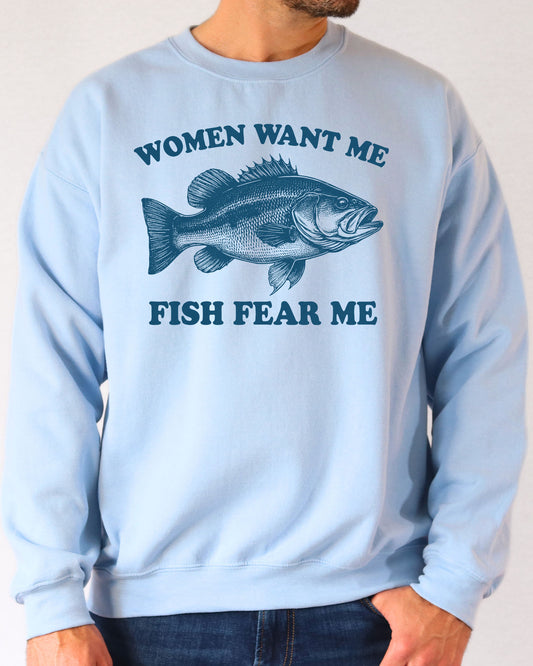Man wearing a light blue sweatshirt with a retro bass fish graphic and the quote 'Women Want Me, Fish Fear Me'.