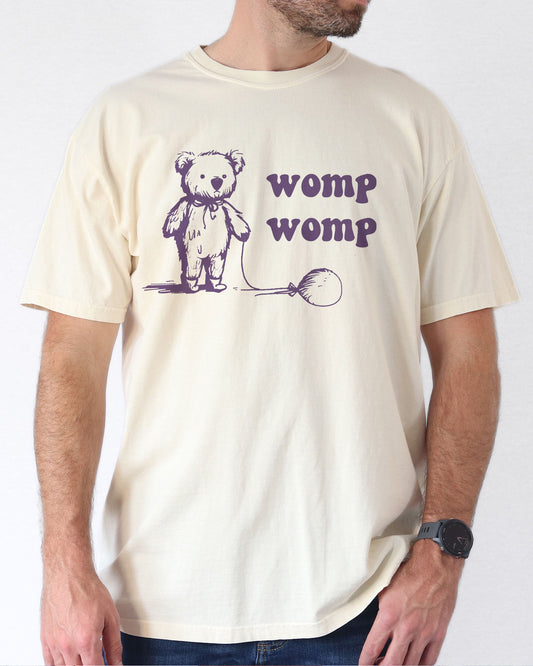 Model wearing natural color shirt with 'Womp Womp' graphic design