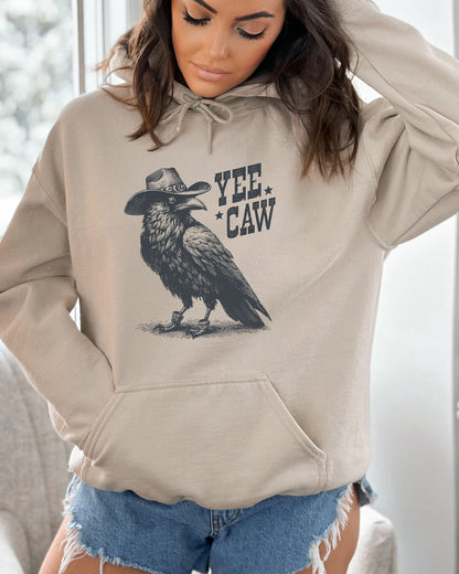 Woman wearing a sand-colored hoodie featuring a funny retro cowboy crow graphic and the quote 'Yee Caw'.