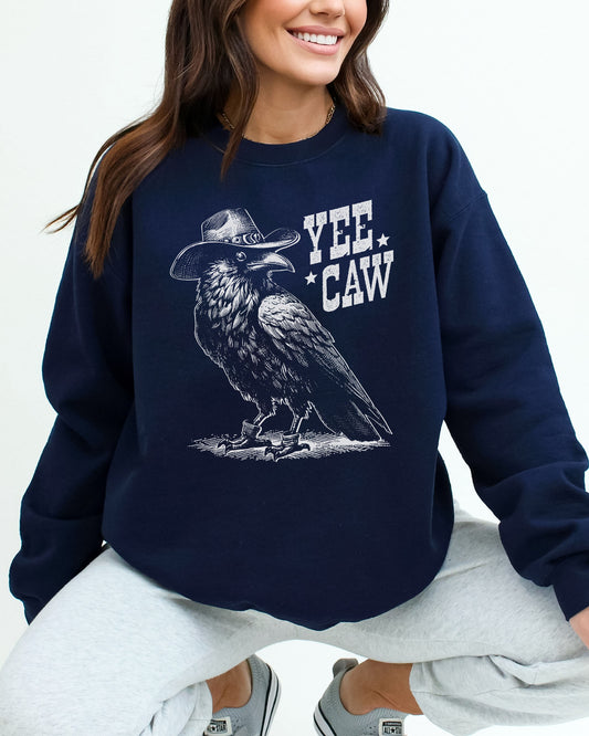 Woman wearing a navy blue sweatshirt featuring a funny retro-style cowboy crow graphic and the quote 'Yee Caw'.