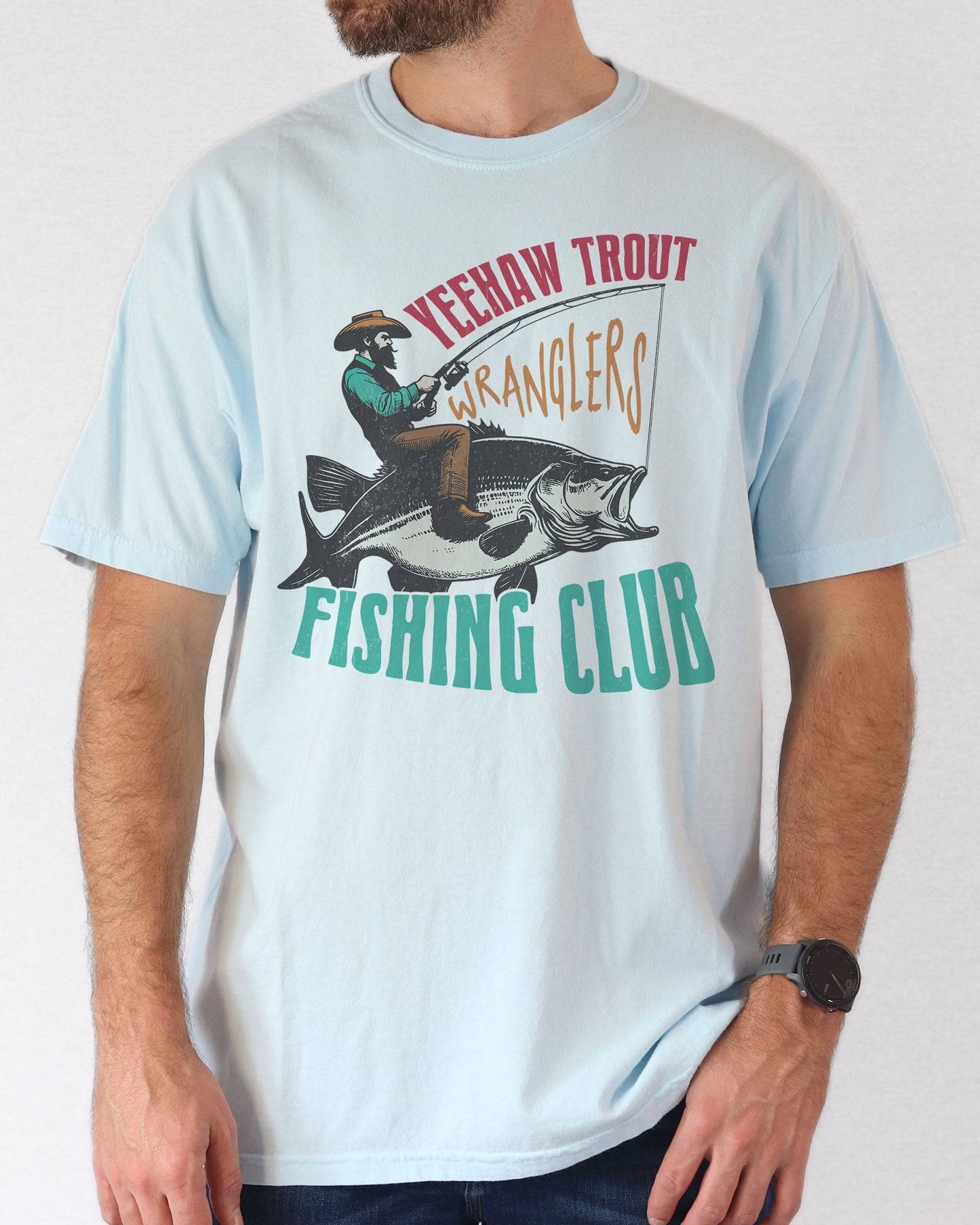 Model wearing chambray color shirt with 'Yeehaw Trout Wranglers Fishing Club' graphic design