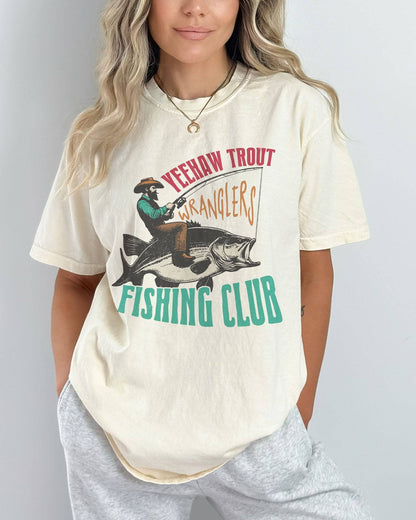 Model wearing ivory color shirt with 'Yeehaw Trout Wranglers Fishing Club' graphic design