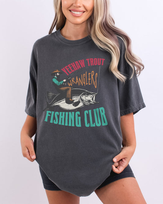 Model wearing pepper color shirt with 'Yeehaw Trout Wranglers Fishing Club' graphic design