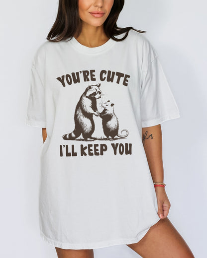 Model wearing white color shirt with 'You're Cute I'll Keep You' graphic design