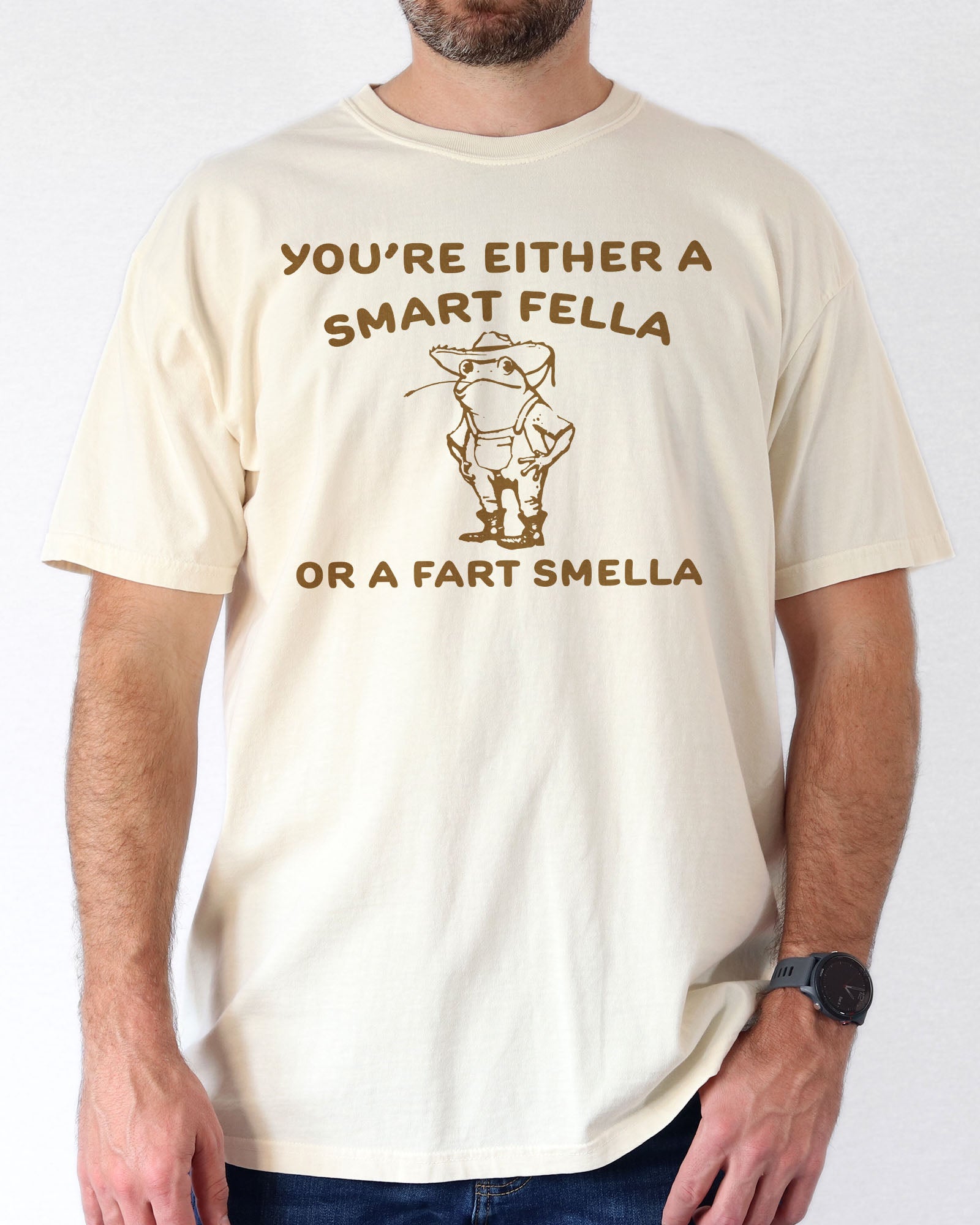 Man wearing an ivory "You’re Either a Smart Fella or a Fart Smella" shirt with a funny retro outline graphic of a cowboy frog.