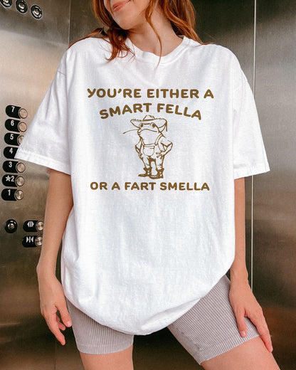 Woman wearing a white "You’re Either a Smart Fella or a Fart Smella" shirt with a funny retro outline graphic of a cowboy frog.