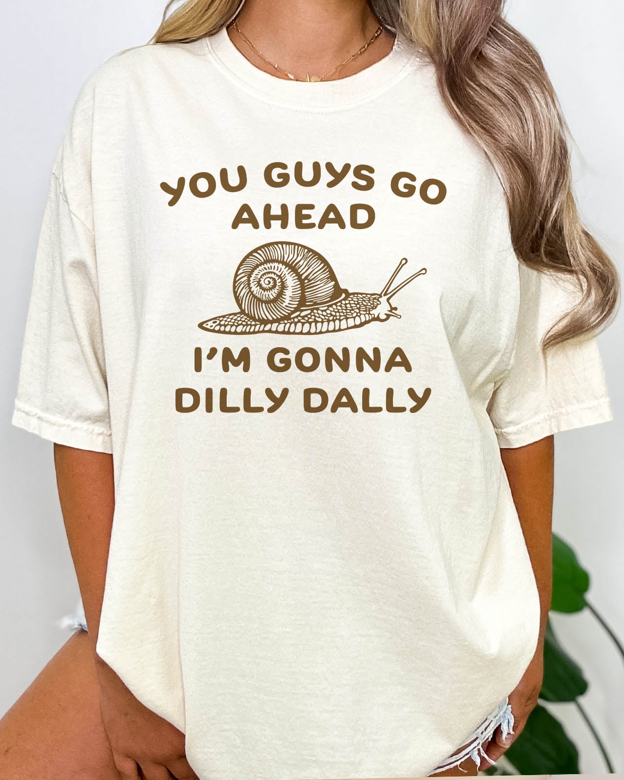 You Guys Go Ahead I'm Gonna Dilly Dally shirt in natural color with a retro snale graphic