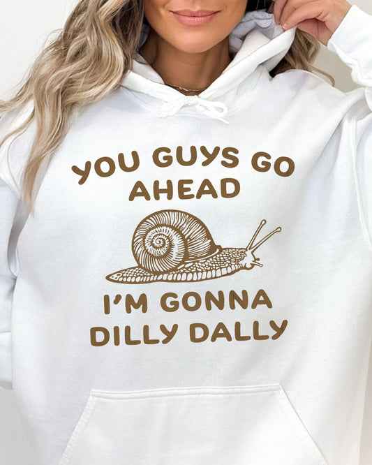 Close-up of a woman wearing a white hoodie with a funny retro-style snail graphic and the quote 'You Guys Go Ahead, I'm Gonna Dilly Dally'.