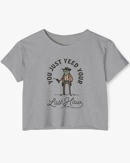 Flat lay of a heather gray crop top with a funny retro cowboy sheriff frog graphic and the text 'You Just Yeed Your Last Haw'.