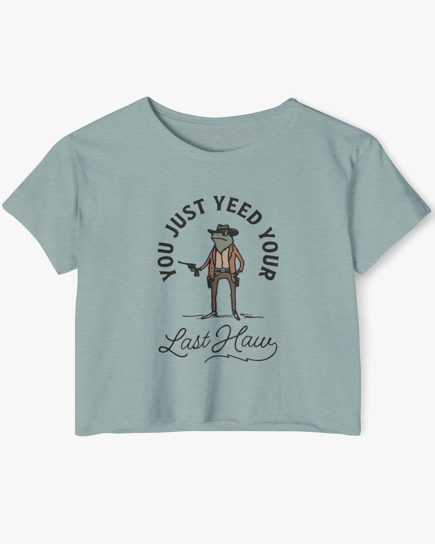 Flat lay of a stonewash green crop top with a funny retro cowboy sheriff frog graphic and the text 'You Just Yeed Your Last Haw'.