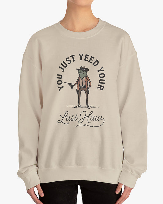 Woman wearing sand beige 'You Just Yeed Your Last Haw' sweatshirt with a funny retro cowboy frog graphic