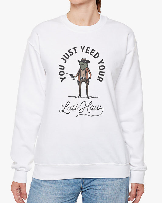 Woman wearing white 'You Just Yeed Your Last Haw' sweatshirt with a funny retro cowboy frog graphic