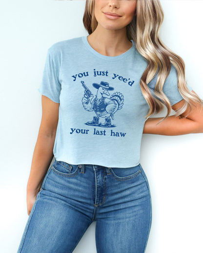Woman wearing a stonewash denim 'You Just Yee'd Your Last Haw' crop top featuring a funny retro cowboy goose graphic.