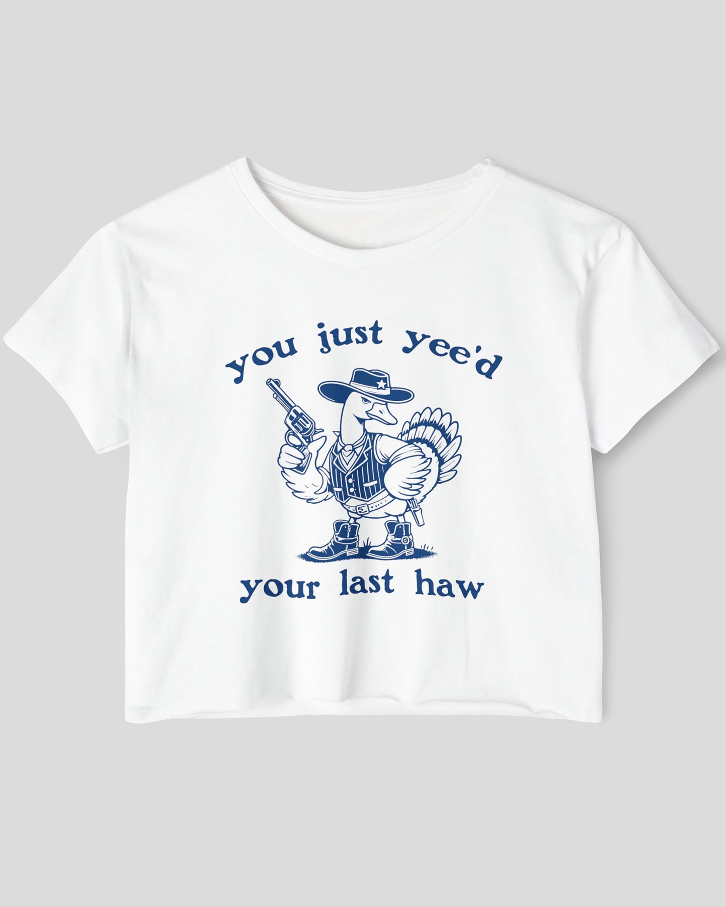 Flat lay of a white 'You Just Yee'd Your Last Haw' crop top featuring a funny retro cowboy goose graphic.