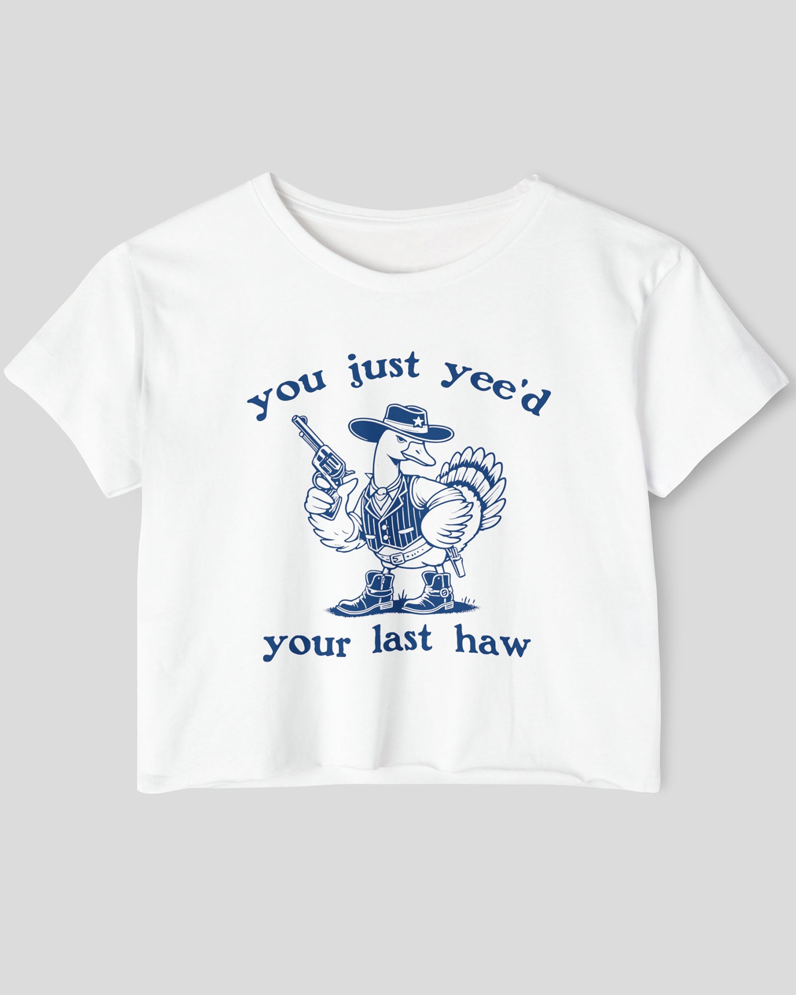 Flat lay of a white 'You Just Yee'd Your Last Haw' crop top featuring a funny retro cowboy goose graphic.