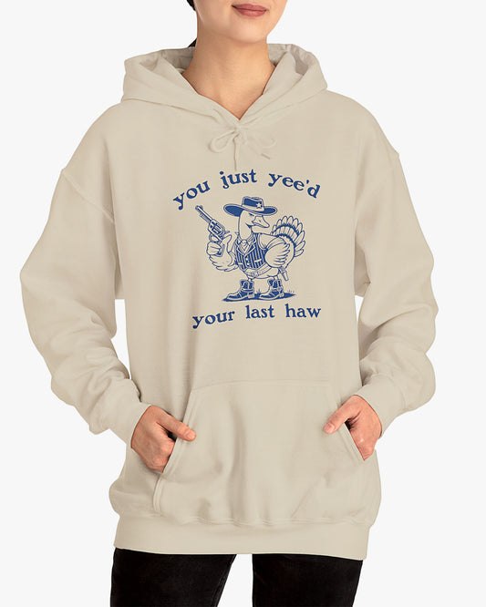 Woman wearing sand beige 'You Just Yeed Your Last Haw' hoodie with funny retro cowboy goose graphic