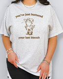 Woman wearing funny retro graphic shirt in ash grey color with the quote "You've Just Buttered Your Last Biscuit"