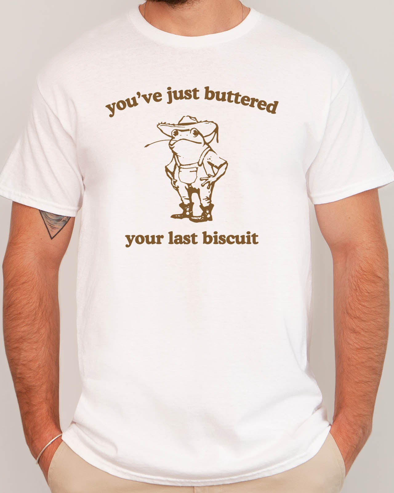 Man wearing funny retro graphic shirt in white color with the quote "You've Just Buttered Your Last Biscuit"