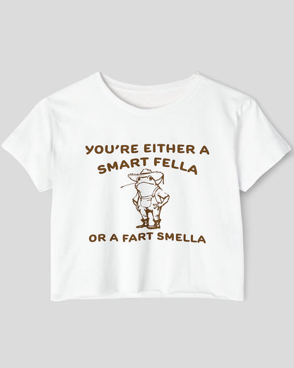 Flat lay white-colored 'You're Either A Smart Fella Or A Fart Smella' crop top featuring a funny retro cowboy frog graphic.
